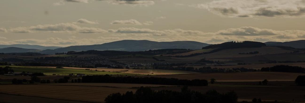 Dramatic landscape with rolling hills and fields under cloudy skies