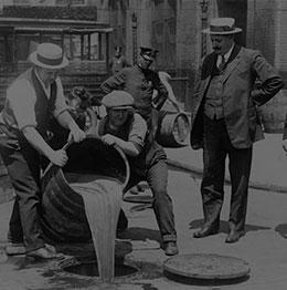 Image of some people pouring some liquid into pothole from barrel